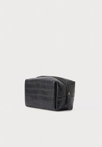 Sort toilettaske i læder med krokodilletekstur, rektangulær form og sølvfarvet lynlåsdetalje langs øverste kant.