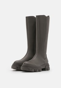 Botas de goma grises hasta la rodilla con un diseño elegante, lados texturizados, suelas gruesas y detalles de costura minimalistas. Ideales para condiciones húmedas.