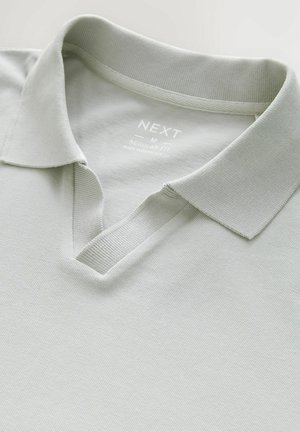 Hellgraues Polohemd mit gestrickter Textur, ausgestattet mit einem klassischen Kragen und einem V-Ausschnitt. Das Etikett aus Stoff gibt an "NEXT, M, Regular Fit."
