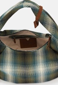 Gemusterte Stofftasche mit einem Farbschema in Blau, Grün und Creme. Verfügt über einen beigen Ledergriff und eine innenliegende Reißverschlusstasche.