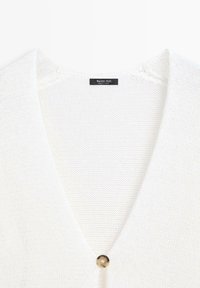 Witte gebreide cardigan met diepe V-hals en enkele ronde schildpadknop, gelabeld "Massimo Dutti, gemaakt in Turkije."