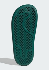 Zelená gumová podrážka sandále s vlnkovým vzorom a vystupujúcou textúrou pre lepšiu priľnavosť. Mierne zakrivený tvar s hrotom v oblasti prstov.