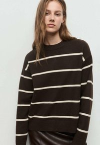 Pulover maro striped cu dungi albe orizontale, guler rotund și mâneci lungi. Material moale, croi lejer, design scurt.