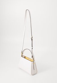 Weiße Lederhandtasche mit strukturierter Form, ausgestattet mit einem Handgriff, verstellbarem Riemen und goldenen Akzenten. Das Innere ist mit gelben Details versehen.