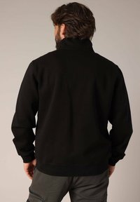 Zwarte sweatshirt met een hoge kraag en geribde manchetten. Gemaakt van zachte stof, met een eenvoudig ontwerp en een klassieke pasvorm.