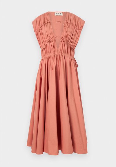 Vestido cor pêssego com mangas curtas e estruturadas, corpete pregueado, decote em V profundo, detalhe de laço e saia fluida. Material de algodão.