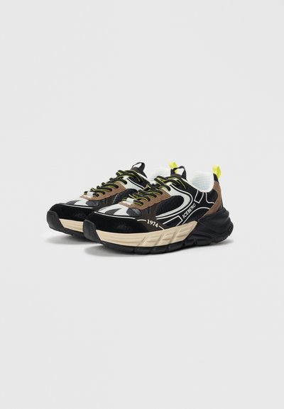Kraftige svarte og brune sneakers med beige såler, heksagonal mønster, neongule detaljer, og "ICEBERG" og "1974" merkevare på sidene.