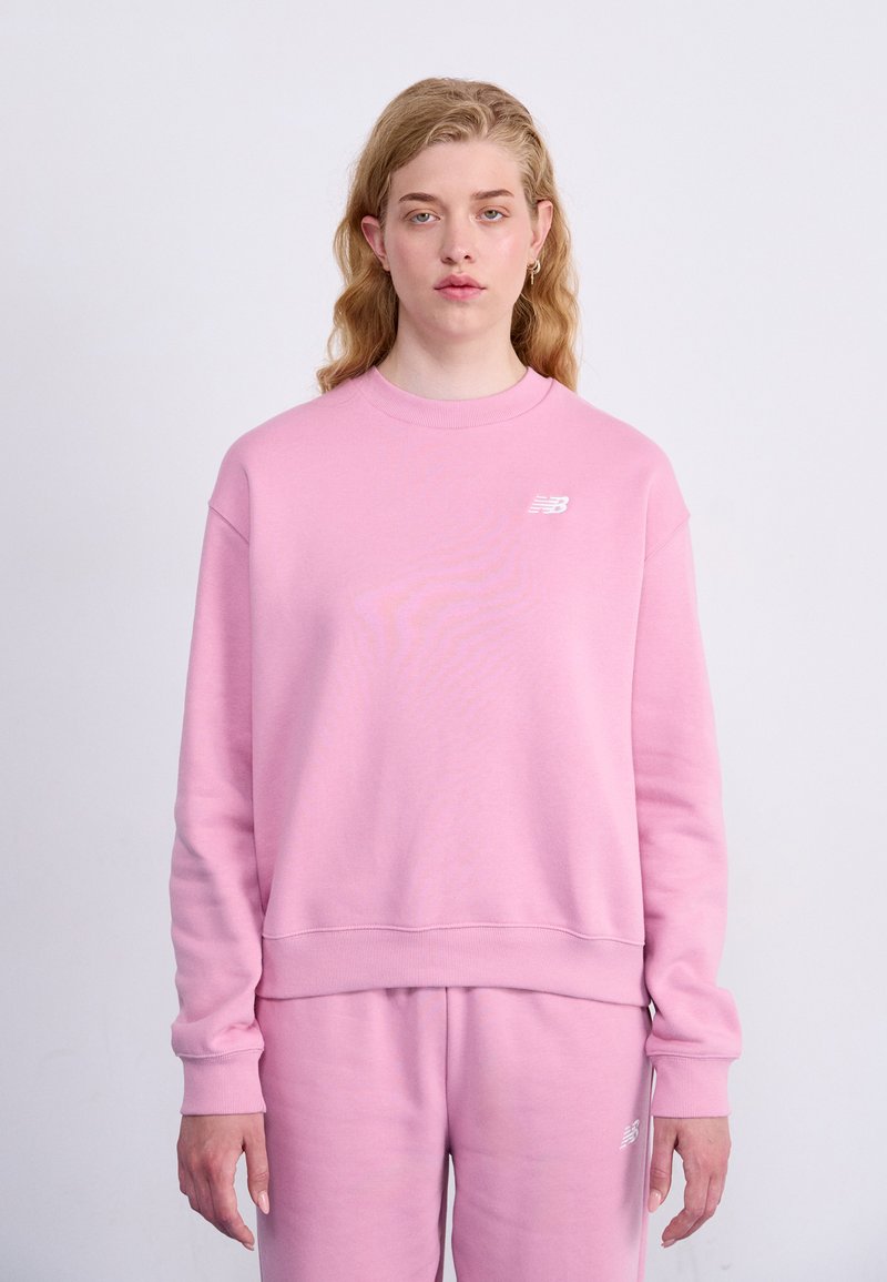 Lichtroze sweatshirt met een ronde hals en geribbelde manchetten, voorzien van een klein wit logo op de linker borst en een relaxte pasvorm.