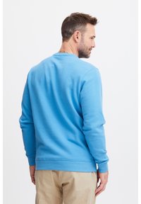 Sudadera de cuello redondo azul claro, mezcla de algodón, corte relajado, puños y dobladillo acanalados, textura suave, sin patrones ni acentos visibles.