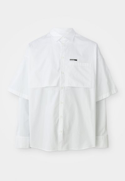 Weißes kurzärmliges Hemd mit Knopfleiste, das eine Brusttasche und ein Markenetikett aufweist. Hergestellt aus leichtem Baumwollmaterial mit glatter Oberfläche.