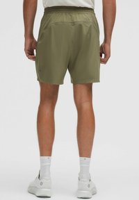 Pantalones cortos deportivos verdes, de longitud a la rodilla, con una cintura elástica y bolsillos laterales. Textura de tela suave, con un pequeño logo en el lado izquierdo.