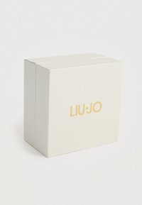 Λευκό κουτί με υφή και χρυσό λογότυπο "LIU·JO" στην μπροστινή πλευρά. Τετράγωνος σχήμα με καθαρές γραμμές και μινιμαλιστικό σχέδιο.