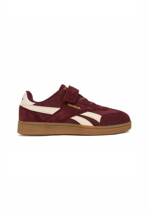 Sidesyn af en burgundy og cremefarvet Reebok-sneaker med gummisål og velcrolukning.