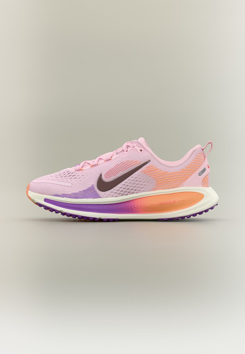 Ανοιχτό ροζ αθλητικό παπούτσι Nike για τρέξιμο με πορτοκαλί και μοβ λεπτομέρειες, μαύρο λογότυπο swoosh και επενδυμένη σόλα πάνω σε απλό φόντο.