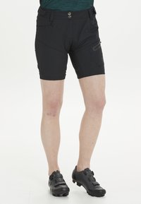 Svarta cykelshorts med en figurnära design, tillverkade av ett stretchigt material. Har fickor och strukturerade detaljer. Bärs tillsammans med svarta cykelskor.