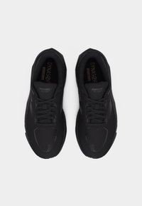 Ζευγάρι μαύρα παπούτσια τρεξίματος New Balance με διχτυωτό επάνω μέρος και κορδόνια, εμφανιζόμενα από πάνω σε λευκό φόντο.