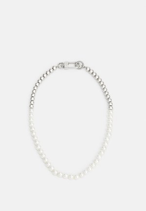 Zilveren en witte parelarmband met metalen sluiting op een eenvoudige lichte achtergrond.