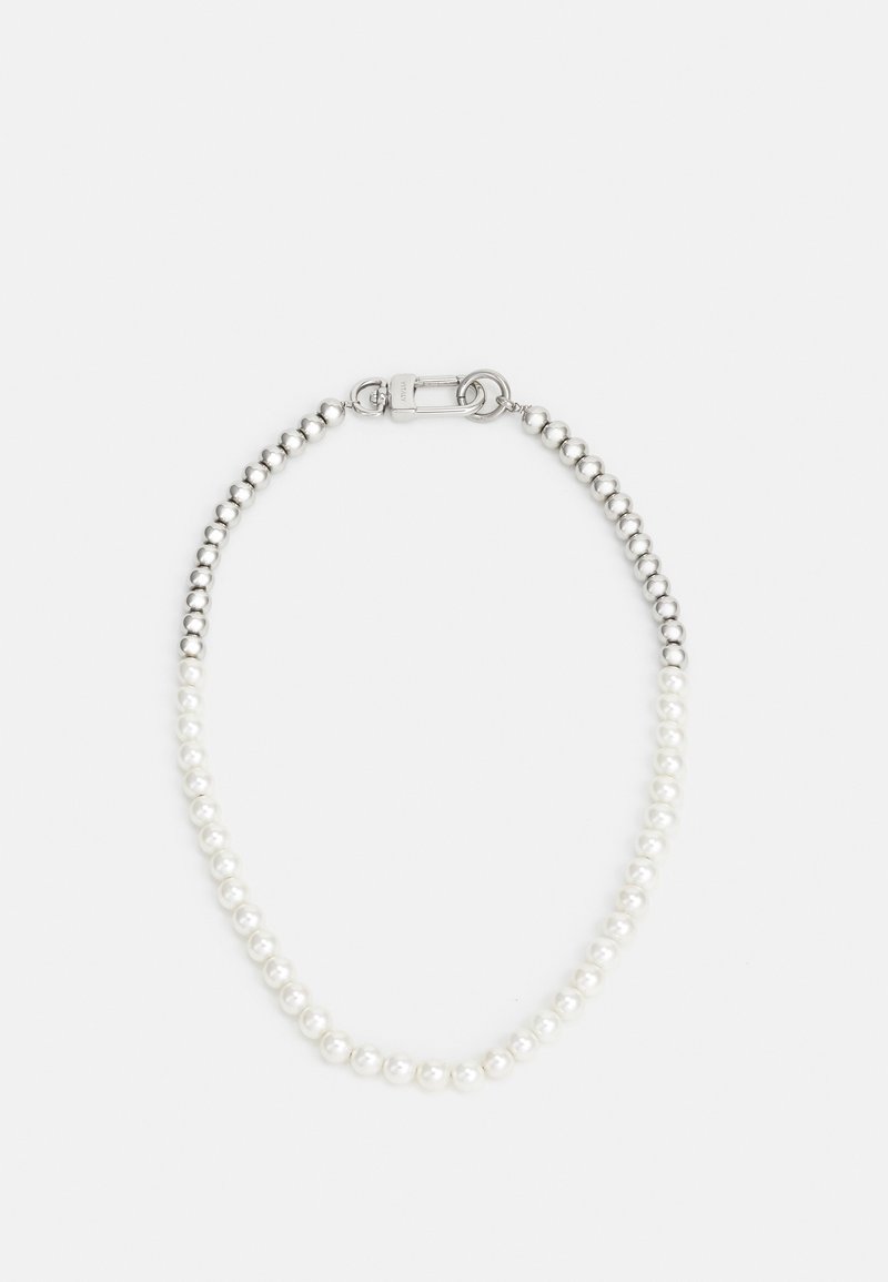 Bracelet perlé de perles argentées et blanches avec une fermeture métallique sur un fond clair uni.