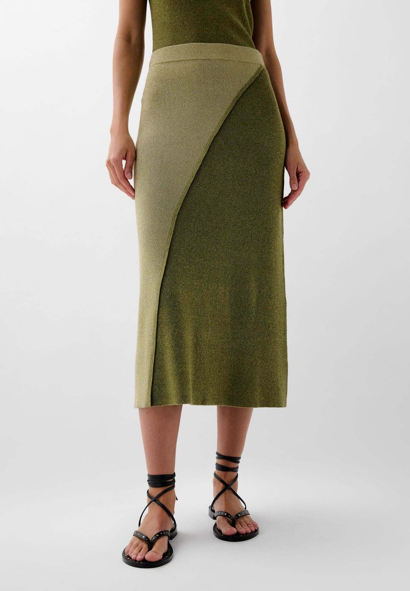 Knælang, olivengrøn ribbskørt med en asymmetrisk design, der har en kontrasterende glat talje og tekstureret stof.