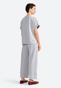Hellgraues, übergroßes Sweatshirt und passende, weit geschnittene Hose aus weichem Stoff mit einem schlichten Design und umgeschlagenen Bündchen. Verstellbares Ausschnitt-Detail.