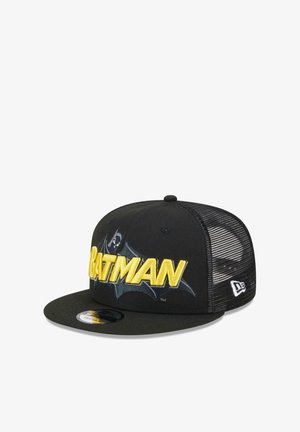 Black baseball cap with yellow "BATMAN" embroidery. Features a solid front and mesh back. Curved brim and logo tag on the side.