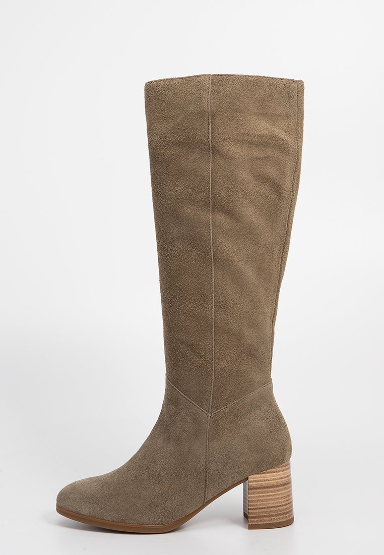 Hohe taupefarbene Wildlederstiefel mit einem gestapelten Blockabsatz und abgerundeter Spitze, von der Seite gegen einen weißen Hintergrund gezeigt.