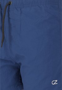 Siniset kevyet uimaportit, joissa on elastinen vyötärönauha ja nyöri. Alareunassa on pieni valkoinen logo. Sileä pinta.