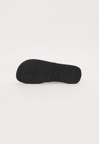 Fekete gumi sneaker talp, textúrált tapadási mintával, középen kiemelkedő "CALVIN KLEIN JEANS" logóval. Simább, tiszta élek.