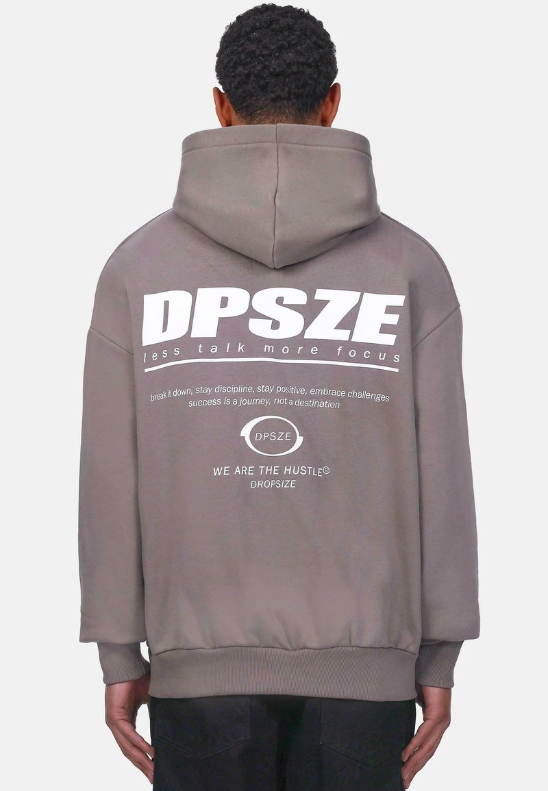 Grauer Hoodie mit einem großen weißen Grafikdruck auf dem Rücken, der den Markennamen und motivierenden Text zeigt. Weicher Stoff, entspannte Passform und gerippter Saum.