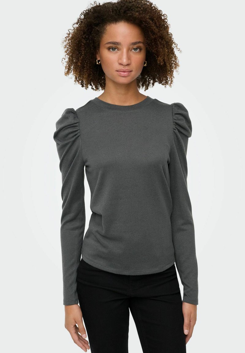 Grå langærmet bluse med pufærmer, rund halsudskæring og en blød tekstur. Kombination med sorte tætsiddende bukser. Enkel og moderne design.