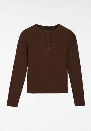 Rudos spalvos ilgomis rankovėmis marškinėliai iš gofruotos medžiagos, suapvalinta apykakle, penkiais mygtukais ir tiesia apačia.