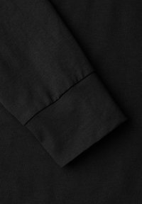 Schwarzes Langarmshirt mit geripptem Bündchen. Glatte Textur mit tailliertem Schnitt. Der Stoff wirkt leicht und flexibel.