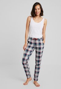 Weißes Trägertop, karierten Schlafanzughose in Grau, Rot und Blau, mit elastischem Bund, Kordelzug und seitlichen Taschen.