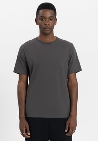 Korte mouwen, ronde hals t-shirt van donkergrijze katoen met een gladde textuur. Rechte onderkant en ontspannen pasvorm. Geen zichtbare patronen of logo's.