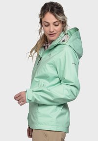 Mintgrüne wasserdichte Jacke mit Kapuze, Reißverschluss vorne und verstellbaren Manschetten. Sie verfügt über eine slim fit und eine leichte, glatte Textur.
