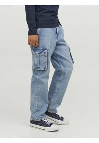 Light blue cargo jeans made of denim with two large side pockets and a relaxed fit, paired with dark blue sneakers.