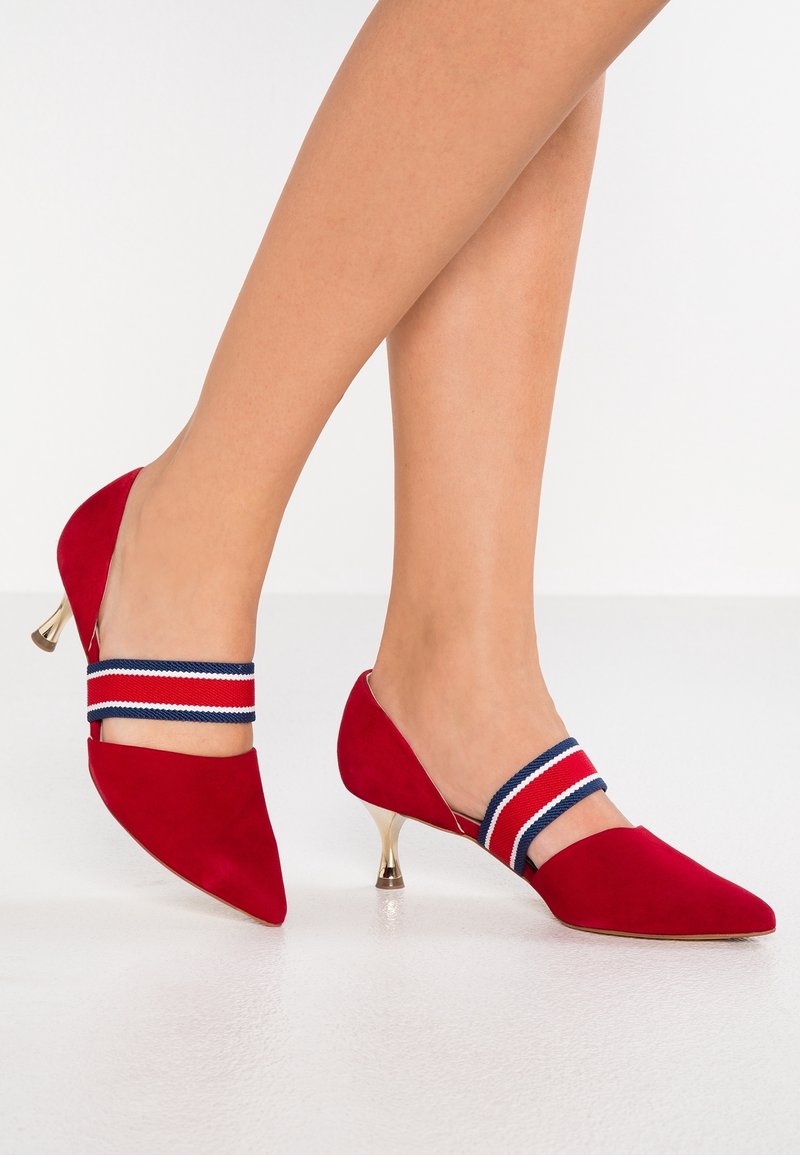 Chaussures à talons hauts en daim rouge avec un bout pointu, dotées d'une bande élastique rayée en marine et rouge, et d'un talon aiguille doré.