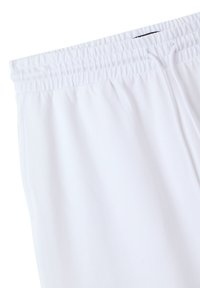 Pantaloni felpati bianchi realizzati in tessuto morbido. Presentano una vita elastica con cordino e tasche laterali. Texture liscia senza motivi visibili.