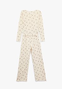 Krämfärgad pyjamasett med långa ärmar och byxor, prydd med ett upprepat brunt mönster av små rosetter. Mjuk tygkvalitet, avslappnad passform.