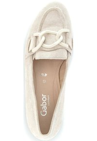 Beige suede slip-on shoe with a rounded toe, featuring a decorative light-colored chain across the upper and embossed brand logo.
