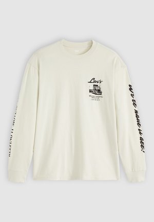 Beżowy t-shirt z długim rękawem. Posiada czarny nadruk graficzny na lewej piersi oraz tekst wzdłuż prawego rękawa. Wykonany z bawełny, w regularnym kroju.