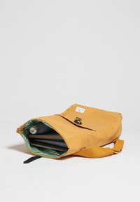 Borsa in canvas gialla con apertura con zip, con un interno a righe verdi e bianche. Include una chiusura con fibbia e una tracolla regolabile.