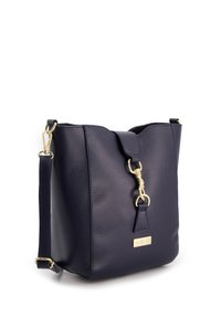 Marinefarbene Leder-Eimerhandtasche mit strukturierter Oberfläche, goldfarbener Hardware und abnehmbarem Tragegurt. Der Verschluss verfügt über einen Überwurf mit Druckknopf.