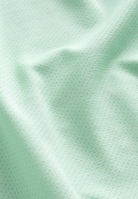 Miętowy materiał o gładkiej fakturze i subtelnym, wypukłym wzorze w kropki. Tkanina wydaje się lekka i elastyczna, prezentując delikatny blask.