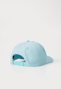 Šviesiai mėlyna kepurė su išlenktu kraštu, tekstūruota medžiaga, reguliuojamas snapback uždarymas ir mažas akcentas šone.