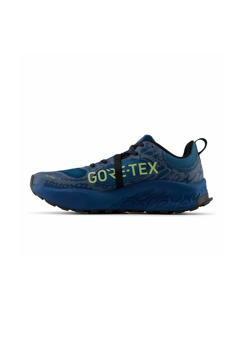 Zapatilla de running azul de Gore-Tex que presenta un upper texturizado, collar acolchado, lazadas elásticas y una suela gruesa con un dibujo para tracción.