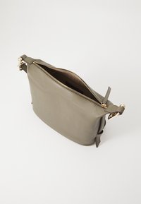 Borsa in pelle verde con dettagli in oro e chiusura a zip. Presenta una tracolla regolabile e una texture liscia. Aperta, mostra l'interno.