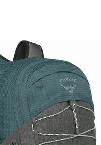 Zaino teal e grigio con tessuto testurizzato, dotato di un logo, cerniere e corde elastiche per il fissaggio dell'attrezzatura. Include spallacci regolabili.