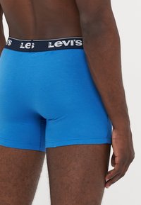 Boxeri din bumbac albastru cu un elastic negru, purtând marca albă "Levi's". Design ajustat, textură fină și cusături minime.
