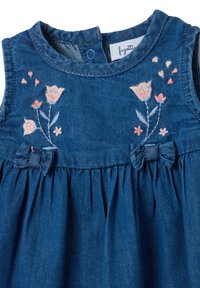 Vestido de mezclilla con escote redondo, patrones florales bordados en rosa y blanco, y una falda fruncida con detalles de lazo en la cintura.